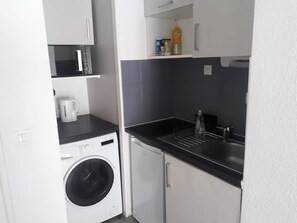 Eine kleine Küchenzeile mit Waschmaschine, Spüle und einer Arbeitsplatte.