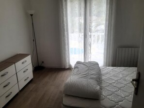 Een slaapkamer met een bed, een dressoir en een vloerlamp.