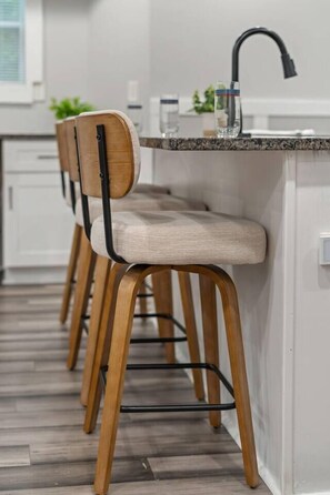 Eine Küche mit Barbereich, Holzstühlen und einem modernen Wasserhahn.