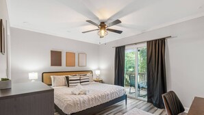 A bedroom with a bed, bedside tables, a ceiling fan, a view through a sliding glass door, and a small balcony. - Stylish 4BR Home Near ATL Airport & Beltline (Atlanta)