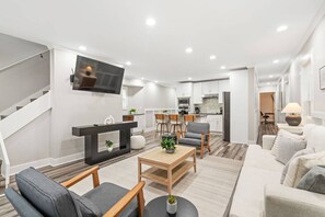 A modern living room with a sofa, chairs, a coffee table, and a TV mounted on the wall. - Stylish 4BR Home Near ATL Airport & Beltline (Atlanta)