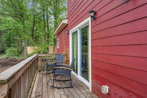 A red wooden deck with two chairs and a table, surrounded by trees. - Stylish 4BR Home Near ATL Airport & Beltline (Atlanta)
