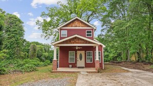 A two-story house with a front porch, a brick chimney, and a small front yard. - Stylish 4BR Home Near ATL Airport & Beltline (Atlanta)