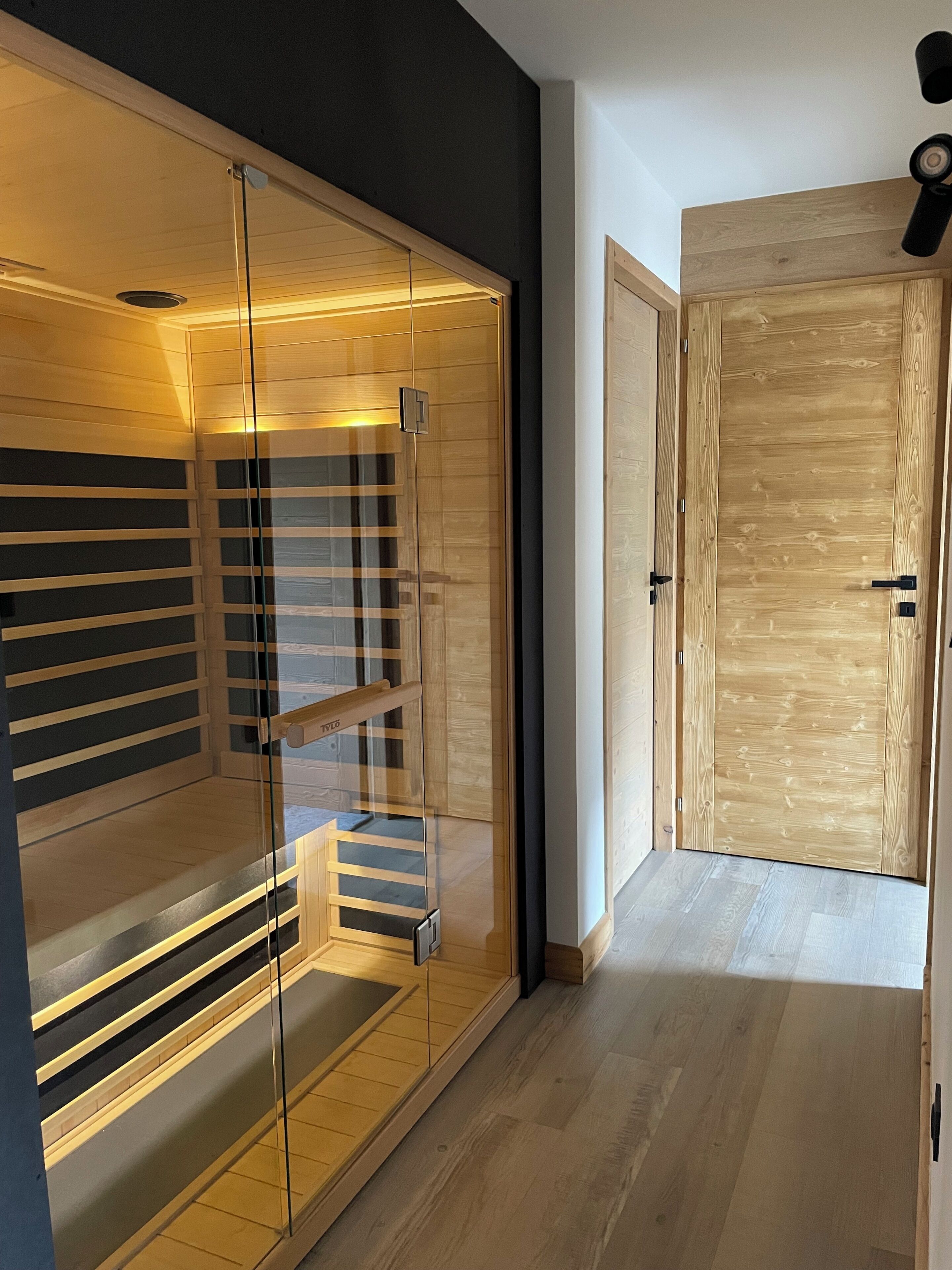 A modern interior with a glass partition, wooden flooring, and a closed wooden door.