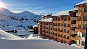 Un centro turístico en la montaña cubierto de nieve, con edificios de madera y una pista de esquí.