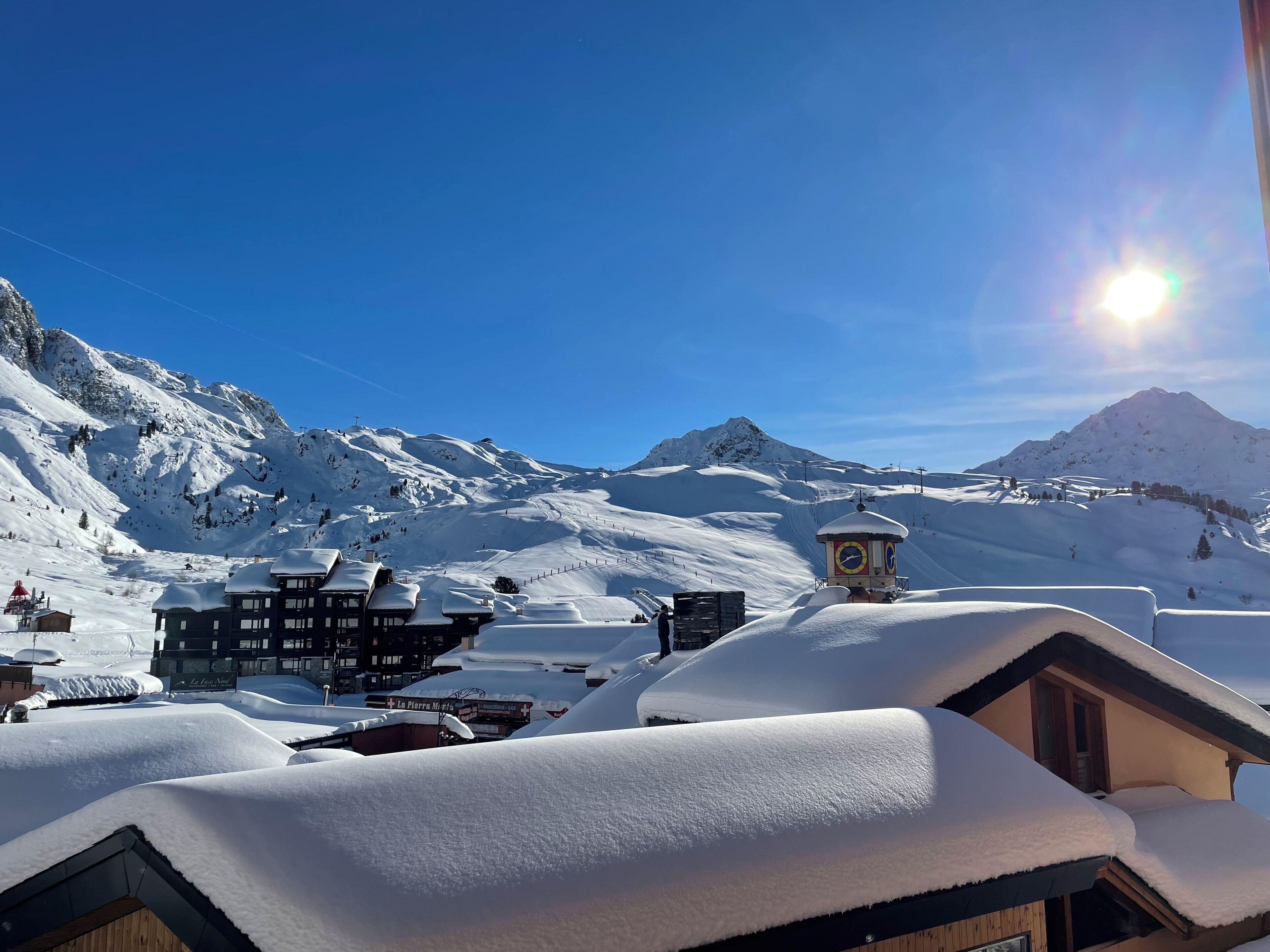 Un village de montagne enneigé, avec des bâtiments et un ciel dégagé.