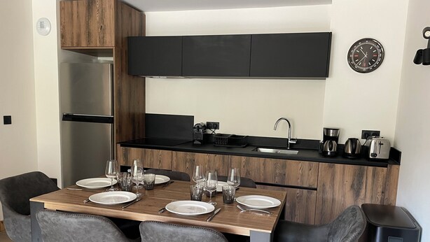 Una cocina moderna con una mesa de comedor para cuatro personas, un refrigerador y una cafetera.