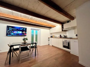 A modern kitchen with white cabinets, a wooden ceiling, and a dining area with a table and chairs. - Cozy apartment in the heart of Veynes with a balcony and a view of the mountains 🏔️ (Veynes)
