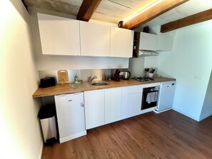 A compact kitchen with white cabinets, a wooden countertop, a built-in dishwasher, and a stove. - Cozy apartment in the heart of Veynes with a balcony and a view of the mountains 🏔️ (Veynes)
