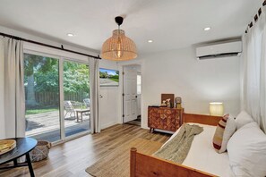 A bedroom with a bed, a dresser, a lamp, and a view of the outdoors through a sliding door. - Sunny Regards Retreat (Fort Lauderdale)