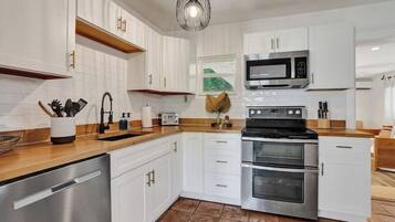 Uma cozinha moderna com armários brancos, eletrodomésticos de aço inoxidável e bancada de madeira.