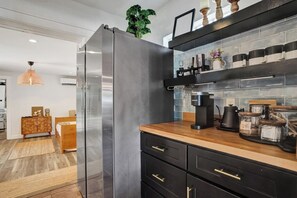 A modern kitchen with a stainless steel refrigerator, black cabinetry, and a coffee maker on the countertop. - Sunny Regards Retreat (Fort Lauderdale)
