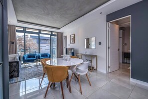Ein moderner Essbereich mit rundem Tisch und Stühlen, einer Couch und Blick durch große Fenster.