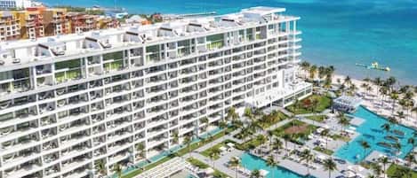 A multi-story hotel with a large pool area and a view of the ocean.