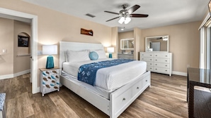 A bedroom with a bed, bedside tables, a ceiling fan, a dresser, and a mirror.