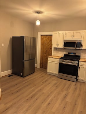 A kitchen with a stainless steel refrigerator, a microwave, and a stove.