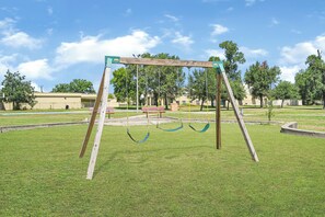 Un parque infantil con columpios y una canasta de baloncesto.