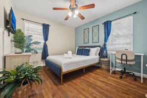 A bedroom with a bed, a desk, a chair, a ceiling fan, and a TV. - Pet-Friendly 2BR Home Near Buckhead ATL (Atlanta)