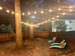An outdoor seating area with lounge chairs and string lights. - Pet-Friendly 2BR Home Near Buckhead ATL (Atlanta)