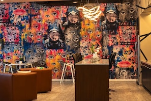 Ein modernes Interieur mit einem farbenfrohen Wandgemälde, einer Bar und Sitzgelegenheiten.