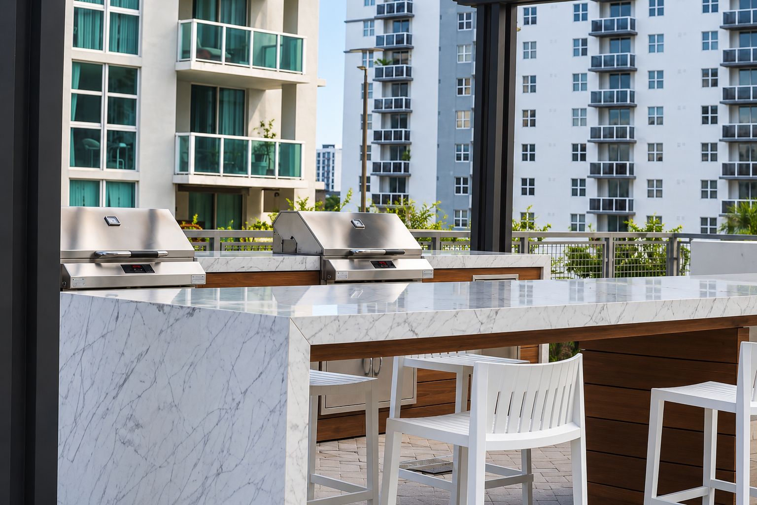 An outdoor bar area with a marble countertop, two built-in grills, and white chairs.