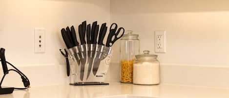 A kitchen counter with a knife block, a jar of pasta, and a jar of rice.