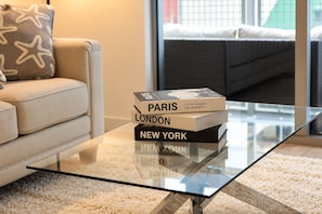 A glass coffee table with a stack of books titled 'Paris,' 'London,' and 'New York.' - 2 Bed Apartment Miami Wynwood Design District Full Amenities (Miami)