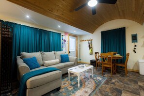 A cozy living room with a sofa, coffee table, and dining area.