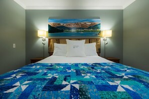 Een hotelkamer met een bed, een schilderij erboven en twee wandlampen.