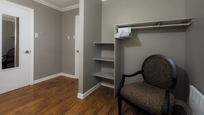 Una habitación con piso de madera, una silla con cojín estampado de leopardo y una puerta blanca.