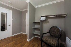 Ein Zimmer mit Holzboden, einem Stuhl mit Leopardenmuster-Kissen und einer weißen Tür.