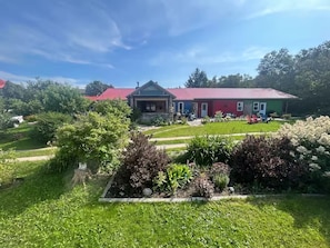 A house with a red roof, surrounded by a well-maintained garden with various plants and a lawn.