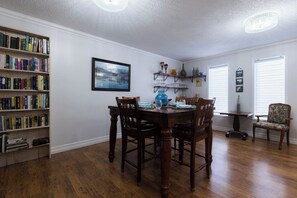 Un comedor con una mesa y sillas de madera, una estantería y un cuadro enmarcado en la pared.