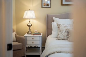 A bedroom with a bed, a bedside table with a lamp, a chair, and a nightstand.