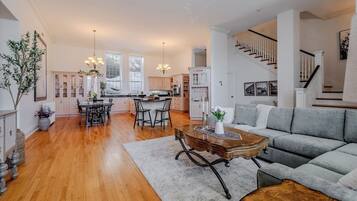A spacious living room with a grey sofa, wooden coffee table, and a dining area with a black table and chairs.