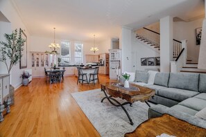 A spacious living room with a grey sofa, wooden coffee table, and a dining area with a black table and chairs.