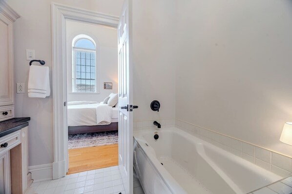 A hotel room with a bathtub, a bed, and a view of the outside.