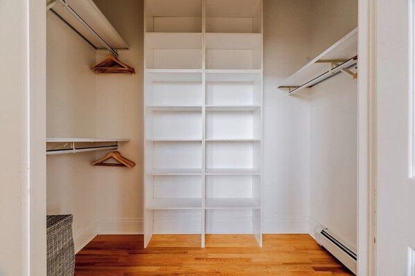 A narrow hallway with a built-in closet featuring multiple shelves and hanging space.