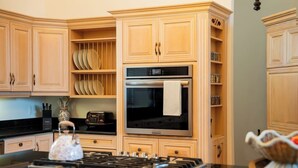 A kitchen with wooden cabinets, a stove, a microwave, and a toaster. - Queens Hall, Historic Luxury in St. John's (St. John's)