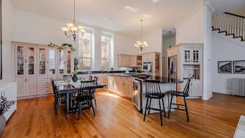 A spacious kitchen with a central island, wooden flooring, and pendant lighting.