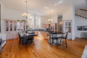 A spacious kitchen with a central island, wooden flooring, and pendant lighting.