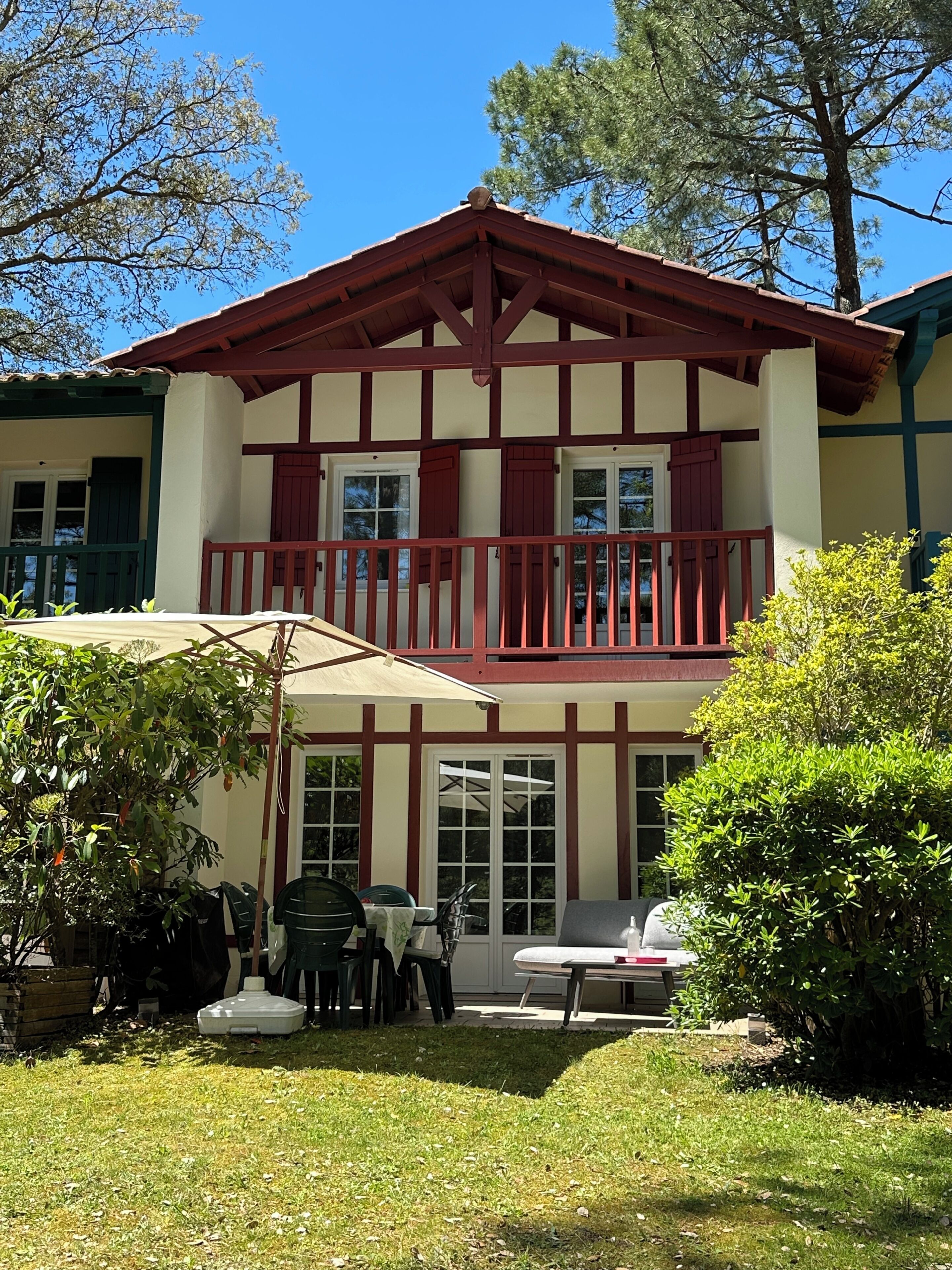Un bâtiment à deux étages doté d’un balcon, d’un espace extérieur aménagé pour s’asseoir et d’un jardin.