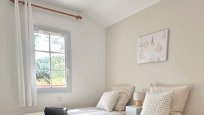 Un dormitorio con dos camas, una ventana con cortinas, una mesita de noche y una obra de arte colgada en la pared.