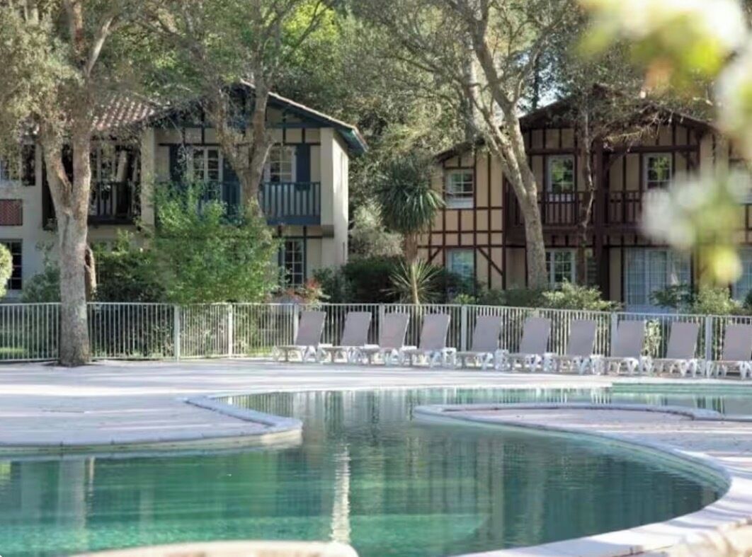 Un espace piscine de forme circulaire, entouré d’une clôture et d’arbres.