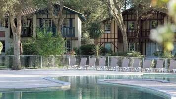 Un espace piscine de forme circulaire, entouré d’une clôture et d’arbres.