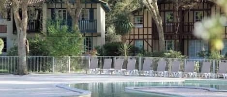 Un espace piscine de forme circulaire, entouré d’une clôture et d’arbres.
