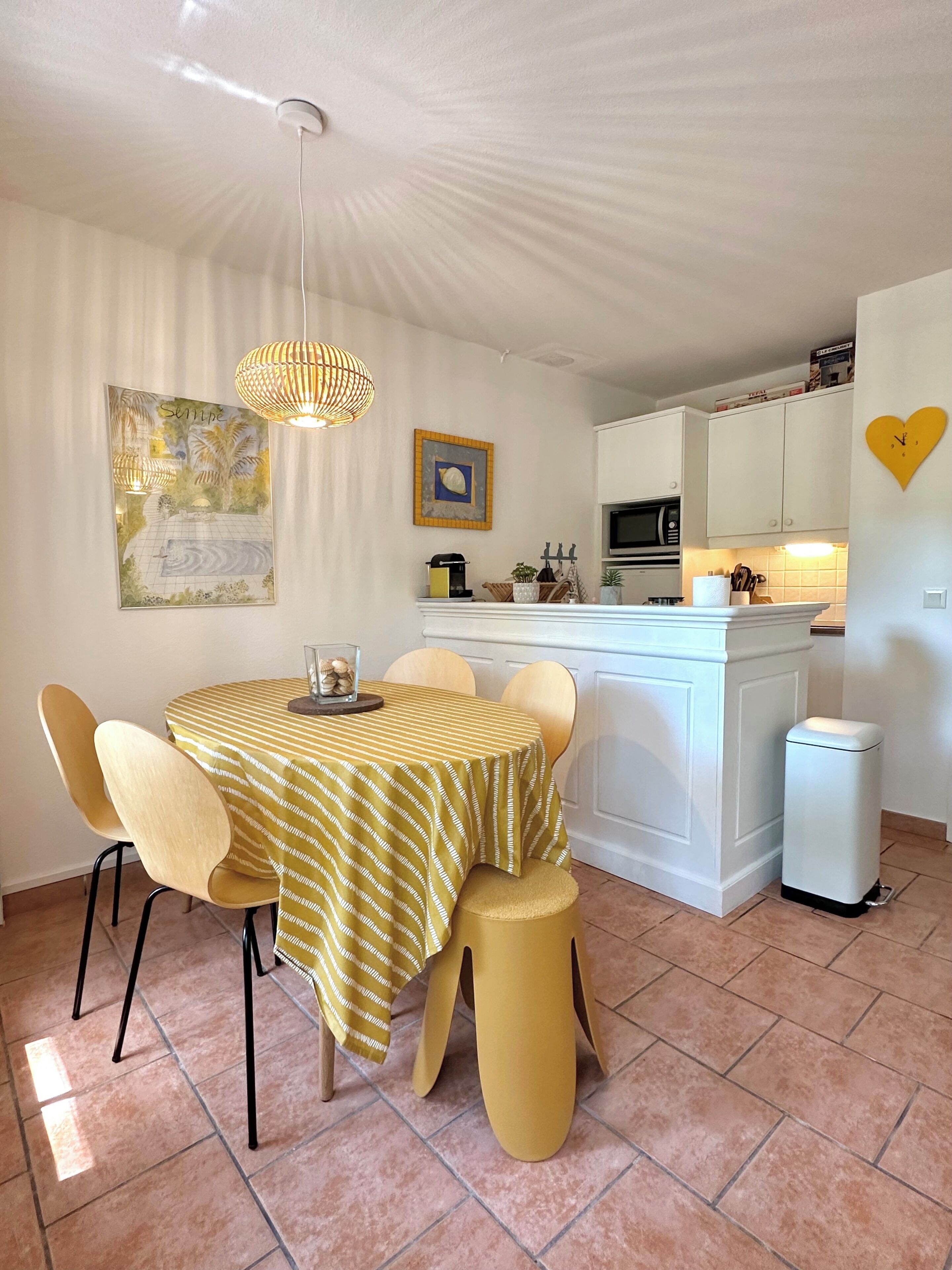 Un coin repas avec une table ronde, des chaises et une nappe à rayures jaunes.