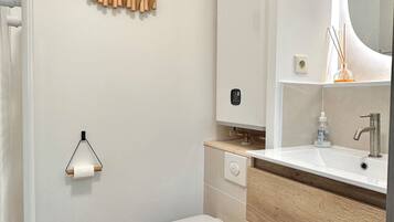 Een moderne badkamer met toilet, wastafel en spiegel.