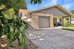 A residential garage with a stone facade, a covered porch, and a clear driveway. - Pool, Fire Pit, Near Beaches | Sleeps 9, Dogs OK (Largo)