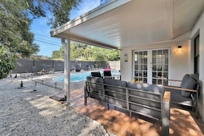 A covered patio with outdoor seating, a swimming pool, and a view of the backyard. - Pool, Fire Pit, Near Beaches | Sleeps 9, Dogs OK (Largo)
